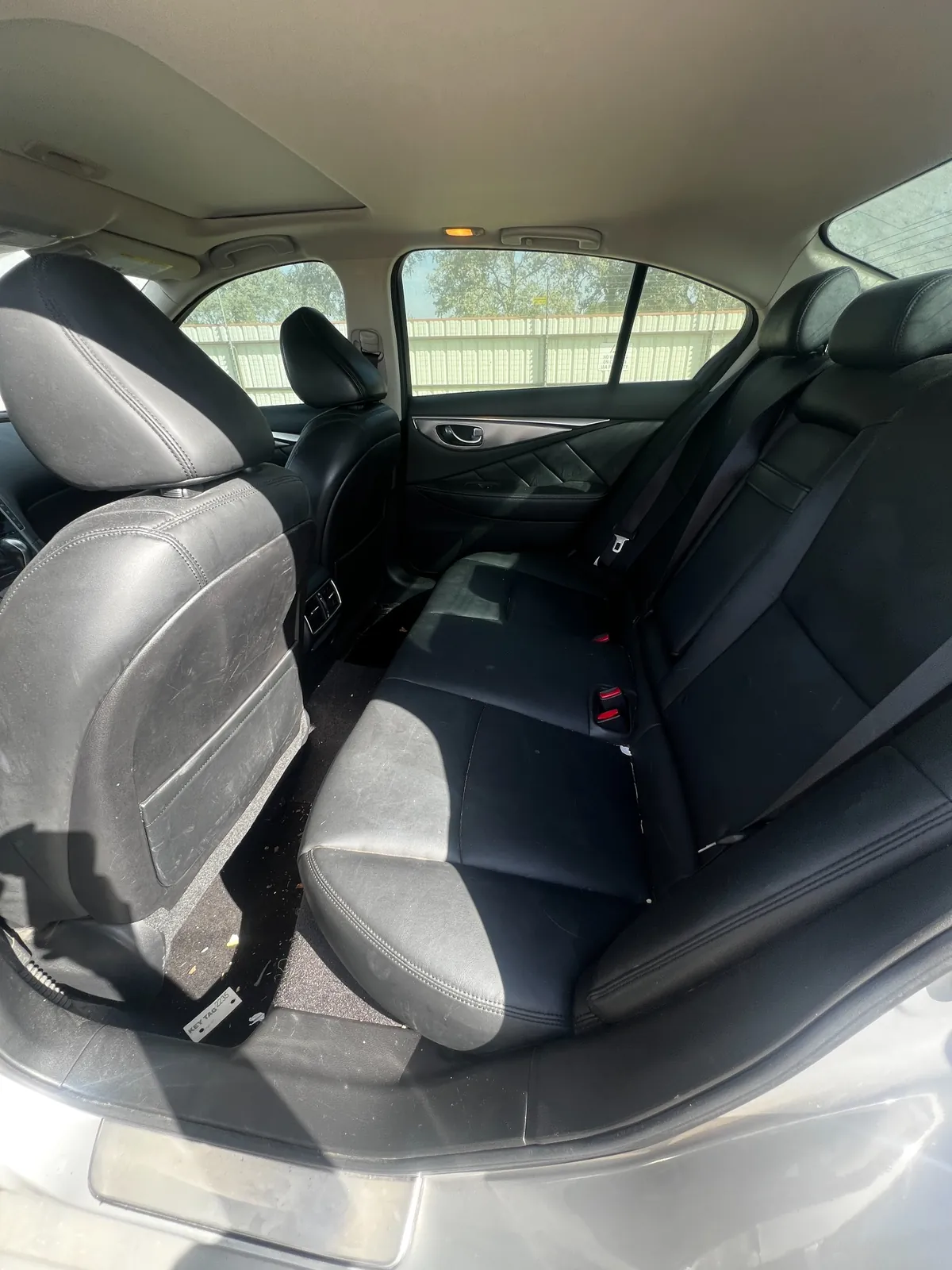 Rear seating area of the Q50 with dusty black leather bench and debris on the floor mats